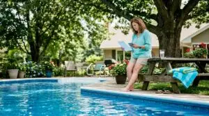 Homeowner reviewing pool maintenance budget at backyard patio