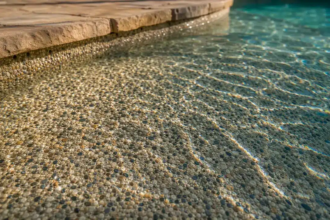 Pebble aggregate pool finish detail in sunlight